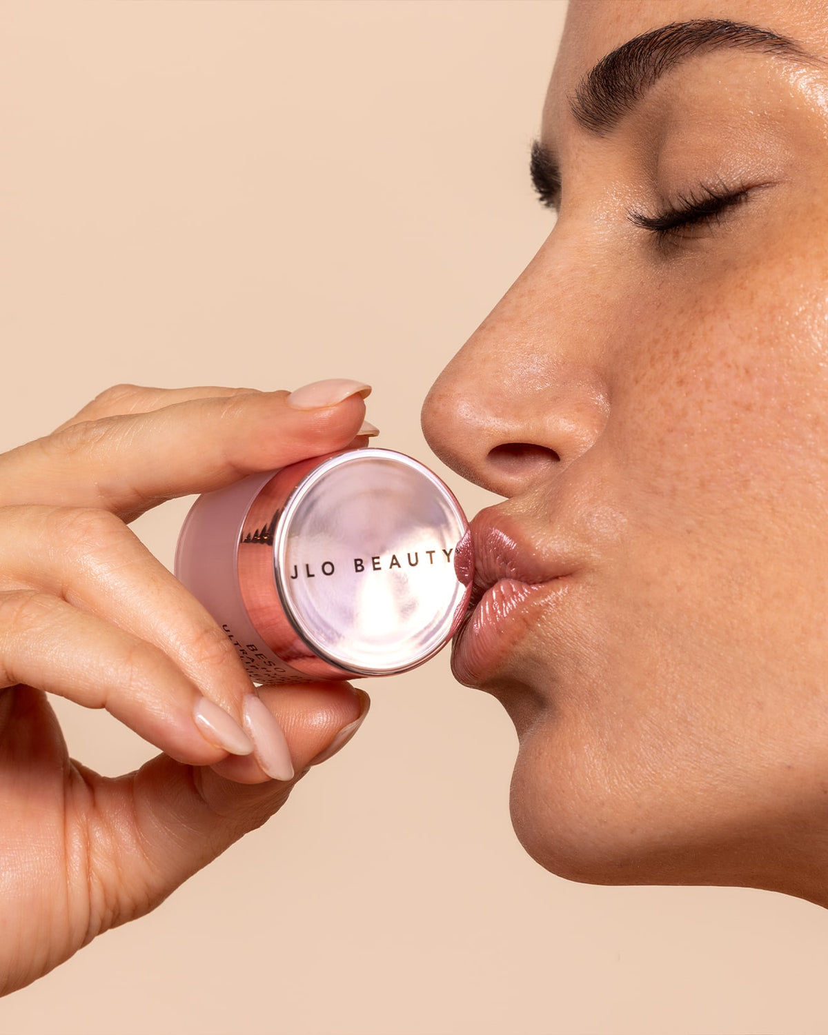 A picture of a woman kissing JLO Beauty skincare.