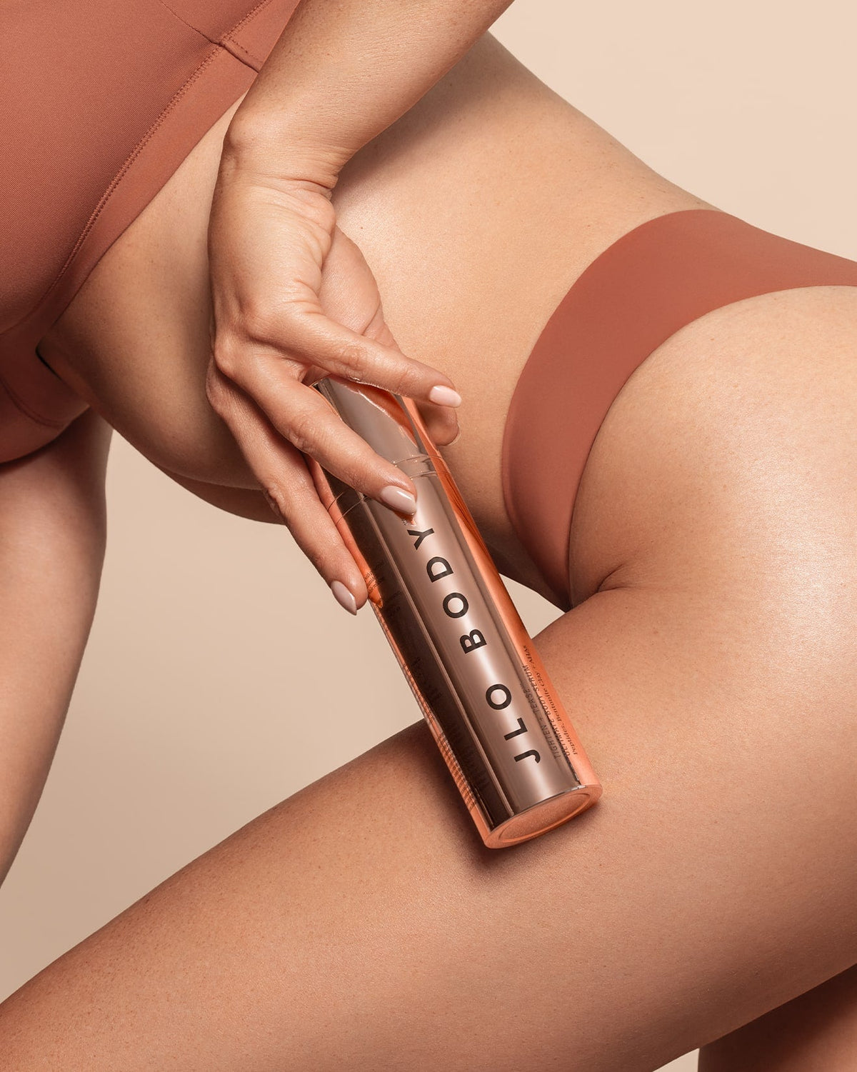 Model applying JLO Beauty Body Serum to her leg.