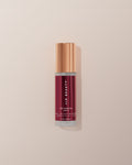 JLO Beauty AHA-BHA bottle in deep burgundy on a neutral background.