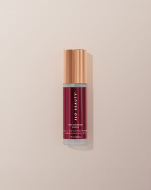 JLO Beauty AHA-BHA bottle in deep burgundy on a neutral background.