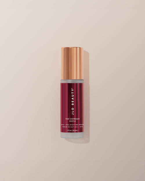 JLO Beauty AHA-BHA bottle in deep burgundy on a neutral background.