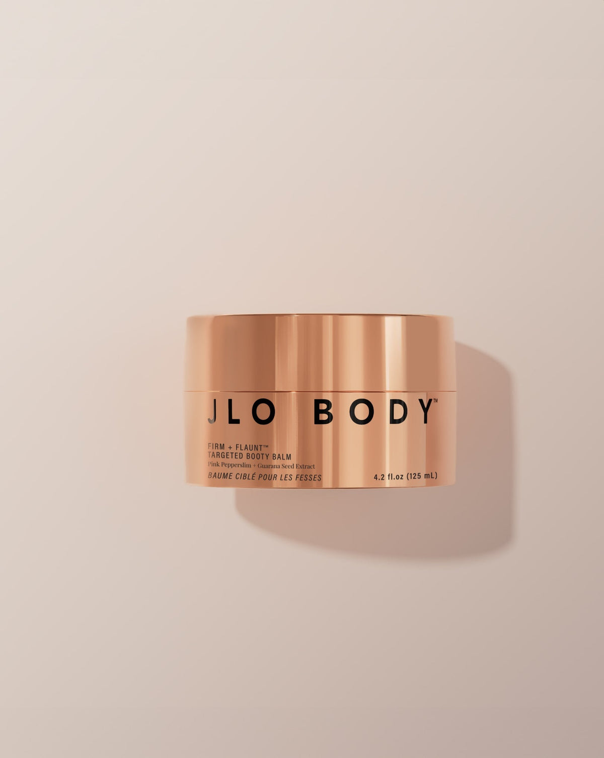 Copper jar of JLO Body balm on a beige background