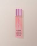 JLO Beauty Glow Mist bottle in soft pink on a neutral background.