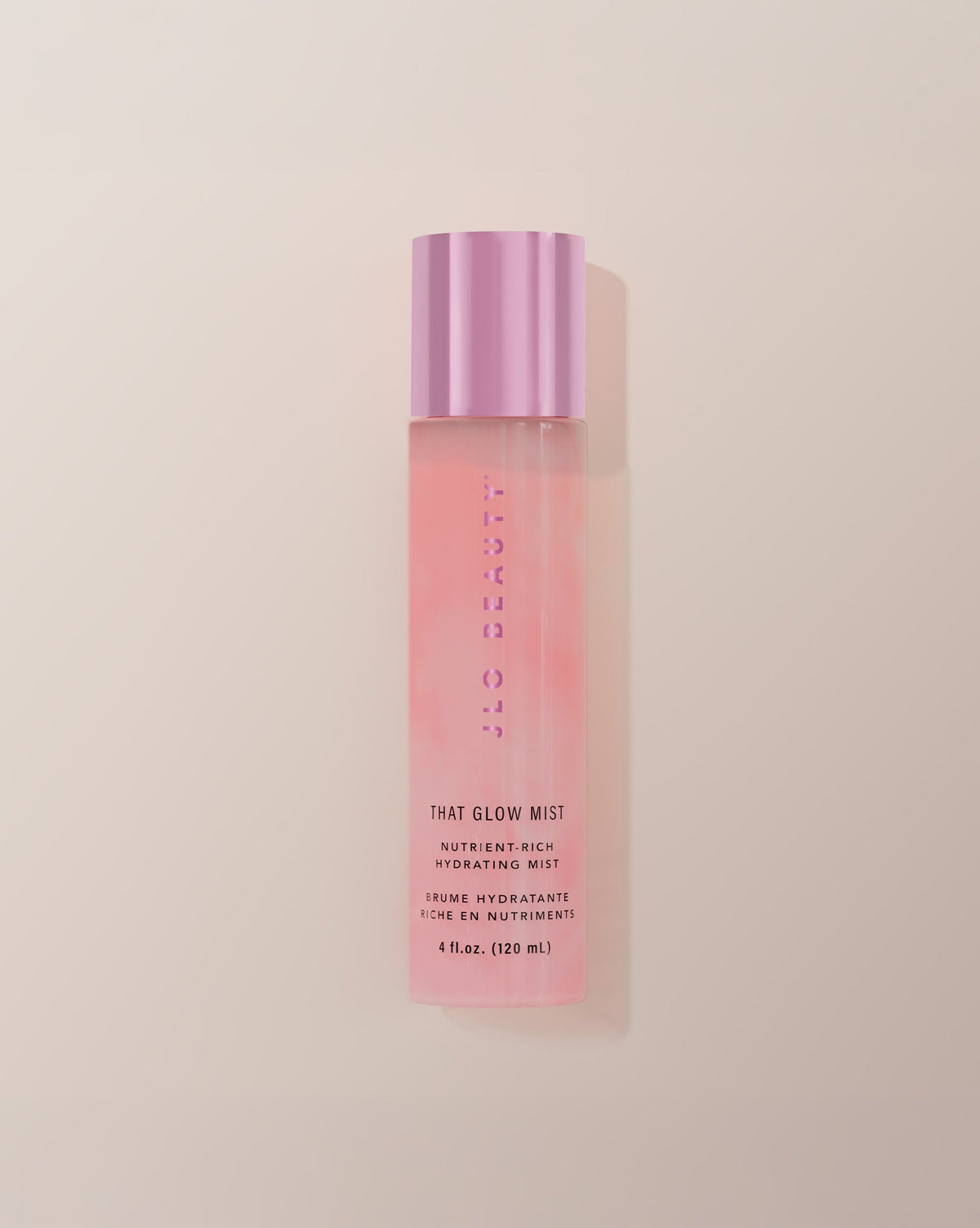 JLO Beauty Glow Mist bottle in soft pink on a neutral background.
