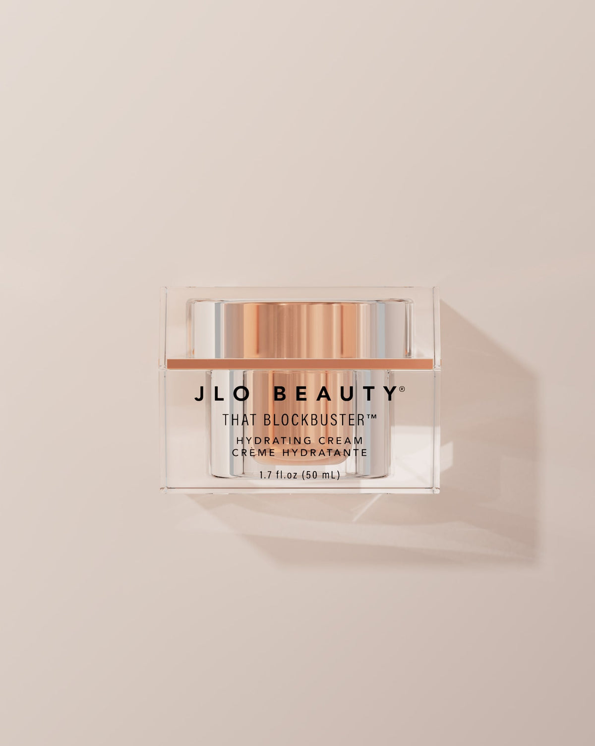 JLO Beauty That Blockbuster Hydrating cream jar on a beige background