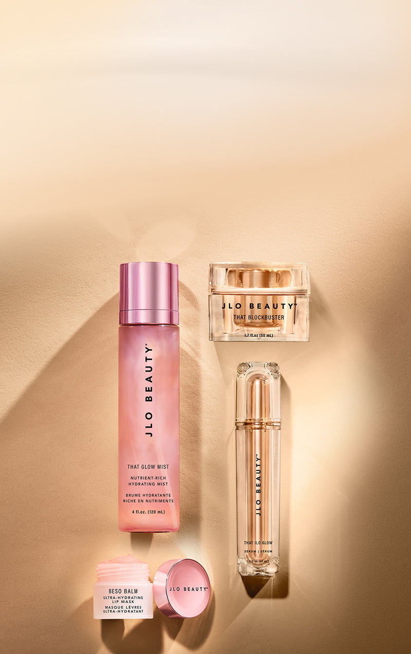 Four JLO Beauty skincare products arranged on a warm beige background with soft shadows.